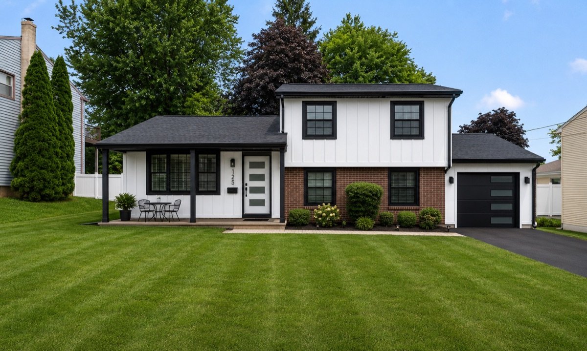 After exterior renovation — new black roof, black windows and white fiber cement siding by Shelby Roofing Services