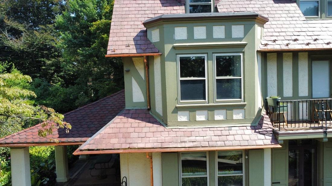 Custom copper half-round gutters and downspouts on a slate-roofed Tudor estate by Shelby Roofing Services