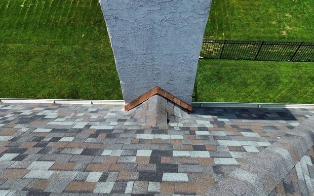 Shingled chimney cricket with copper flashing on a Shelby Roofing Services project