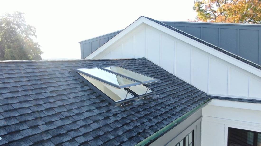 An open venting skylight on an architectural shingle roof
