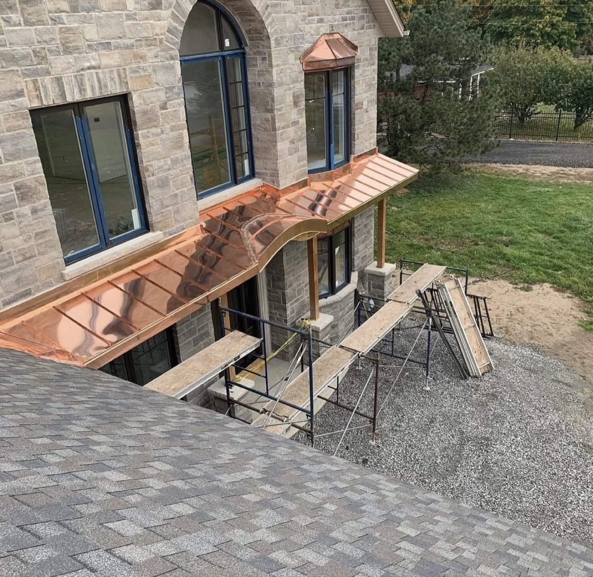 Custom copper metal roof installation by Shelby Roofing Services — copper bay roof on stone estate home