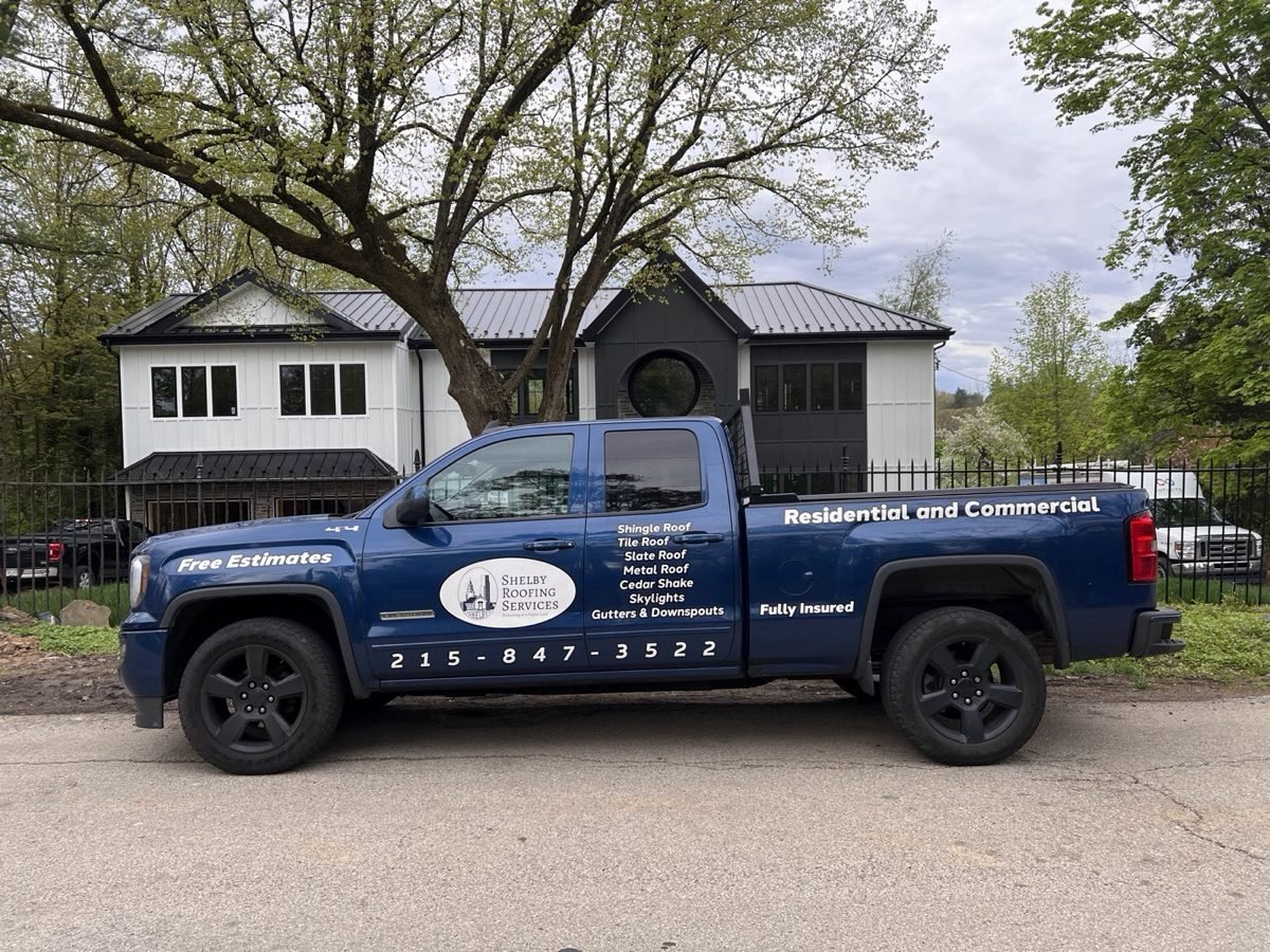 Shelby Roofing Services branded truck parked in front of a completed standing seam metal roof home