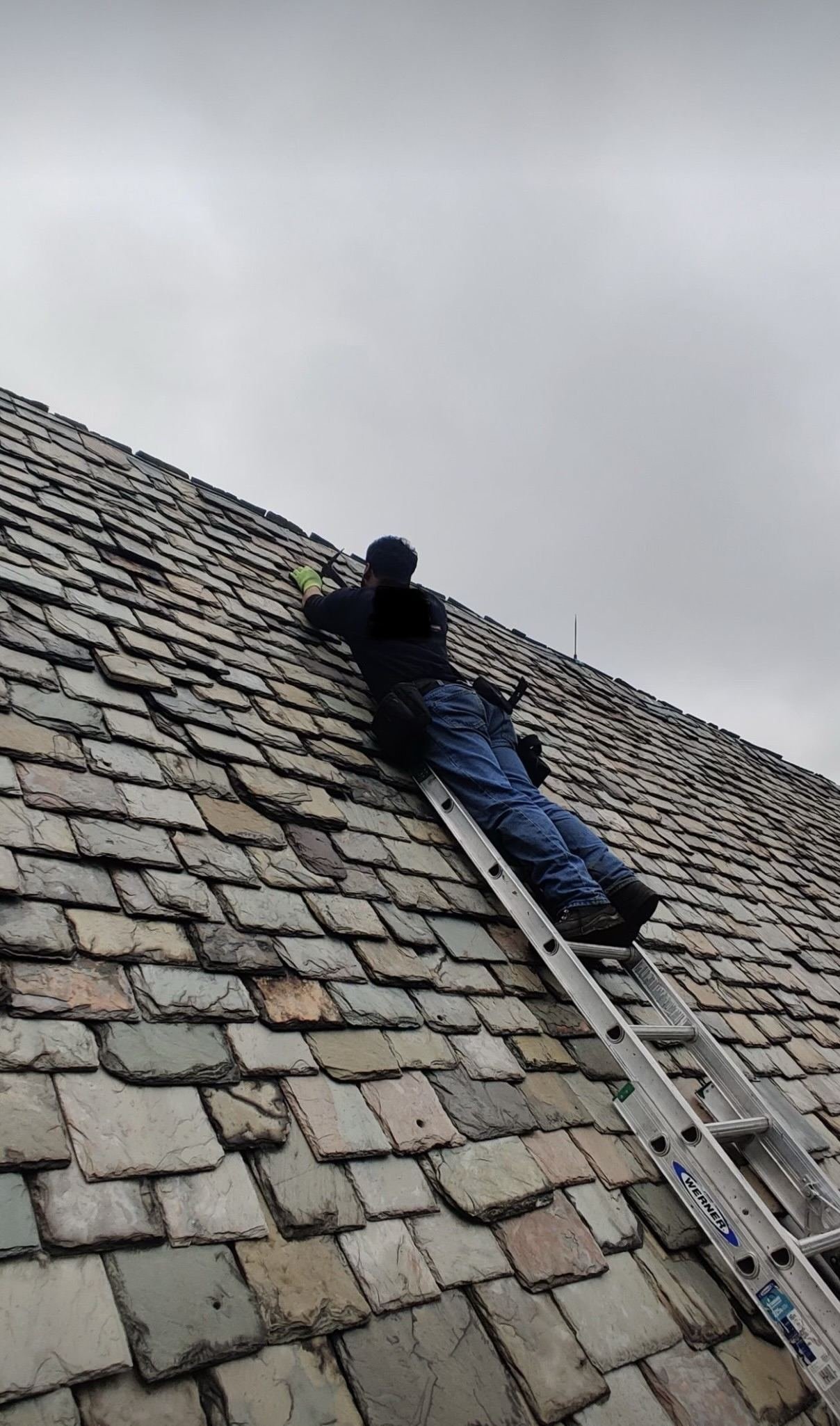 Miguel Cespedes on a ladder performing slate roof repair — specialized slate roofing work, Pennsylvania
