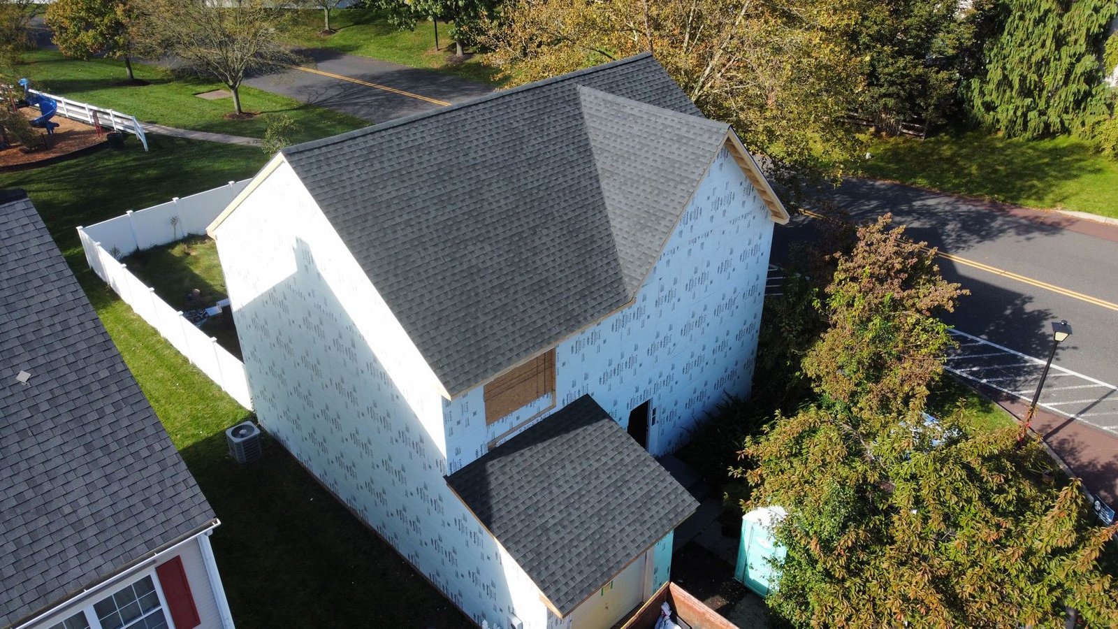 In-progress — side aerial showing scope of full exterior renovation with house wrap, PA