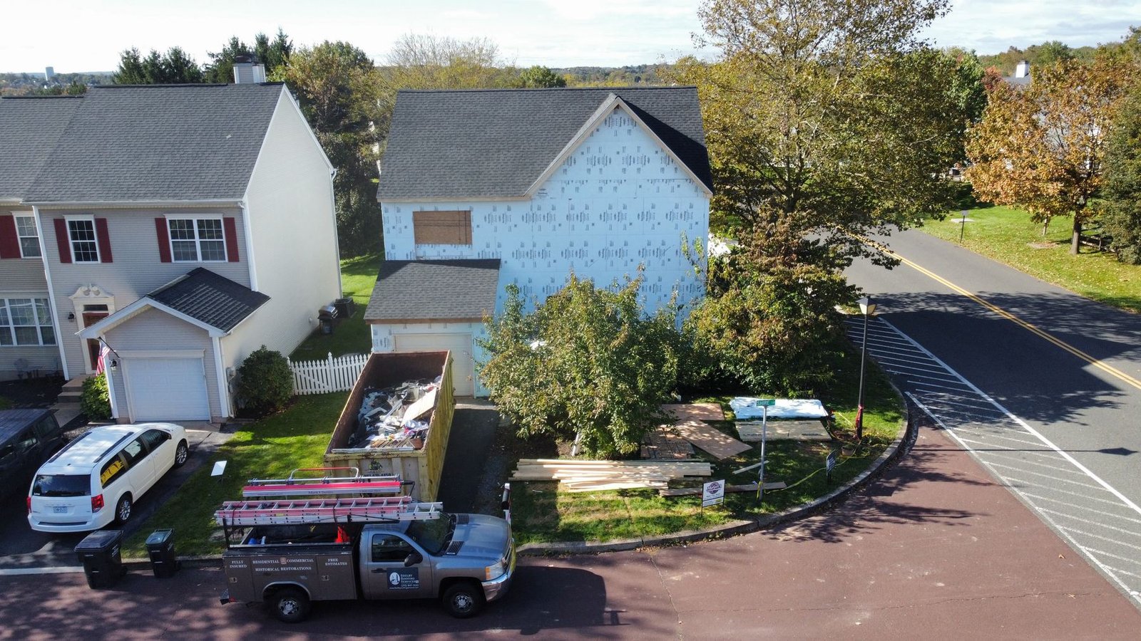 In-progress — full exterior renovation with siding stripped and new roof installed, Shelby truck on site, PA