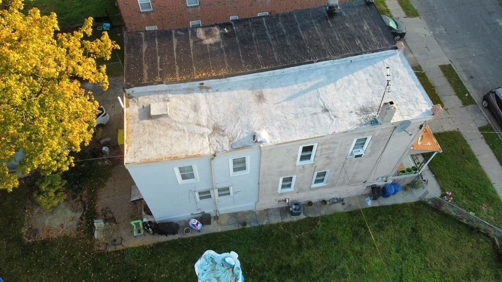 Before — aerial showing failed flat roof with emergency tarp and water damage, PA