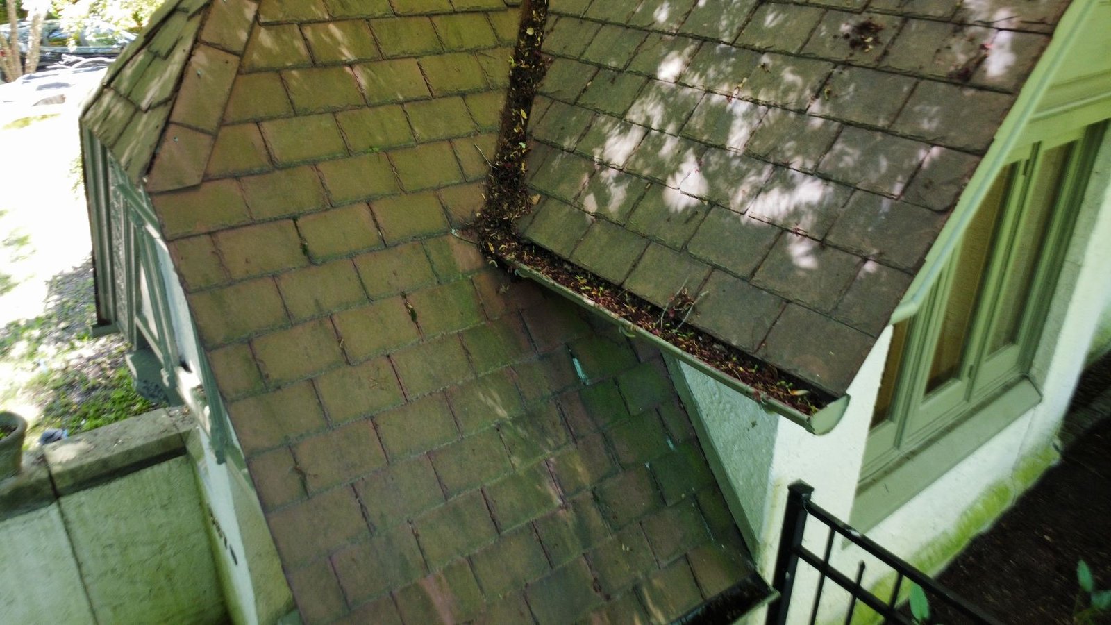 Before — close-up of old clogged gutter with debris and organic growth on slate tile roof, PA