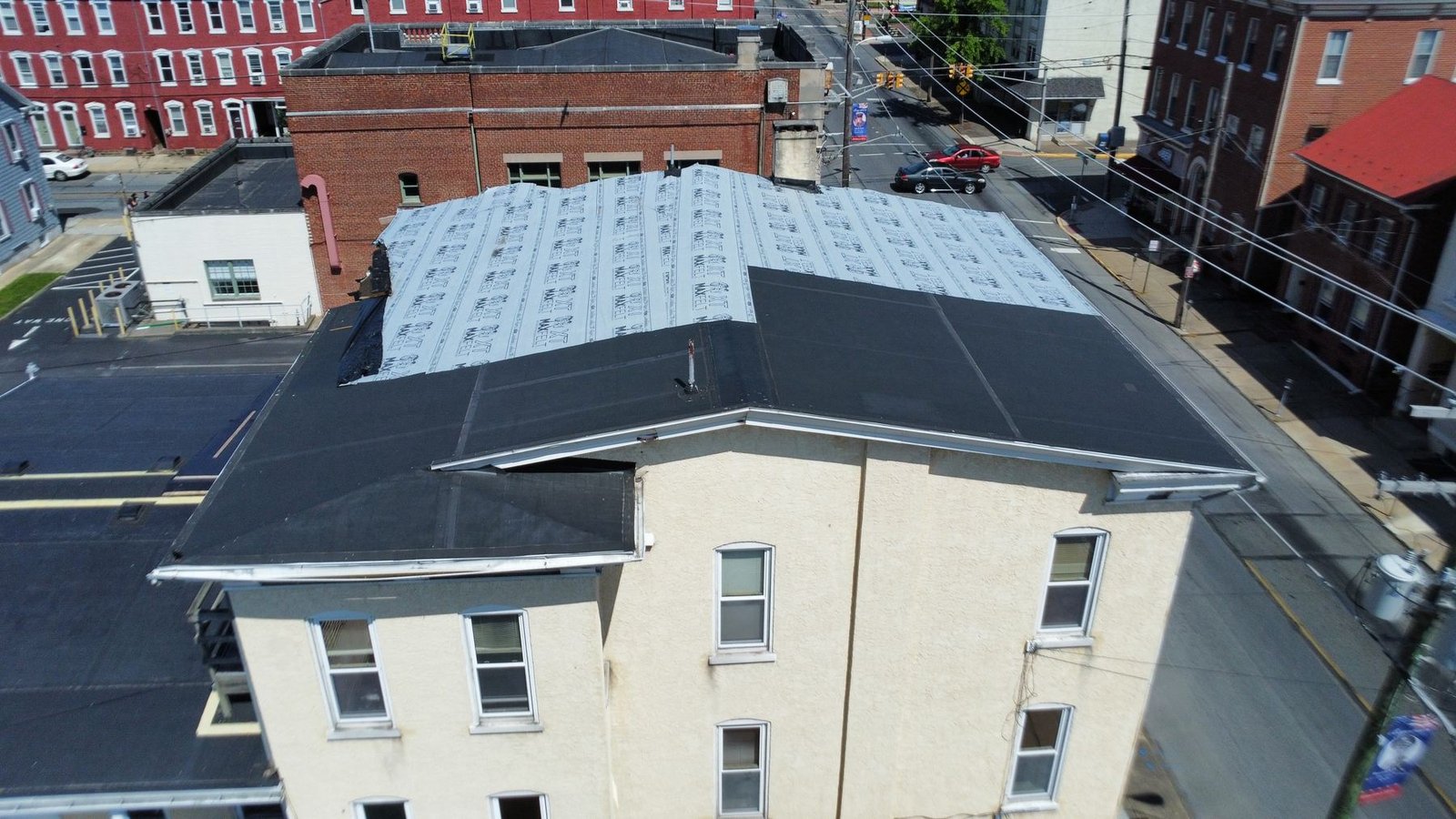 Before — additional angle of commercial building showing partial EPDM failure and exposed decking, PA