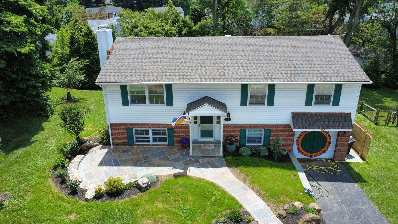 After — front of split-level home completely transformed with new shingles, siding and stone patio — Shelby Roofing Services PA
