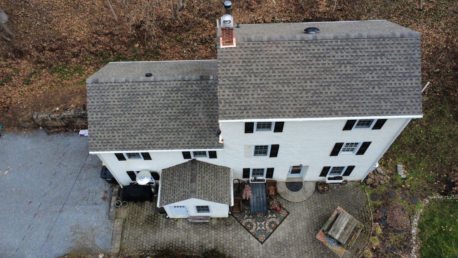 After — top-down aerial of completed white cottage with new clean gray shingles — Shelby Roofing Services PA