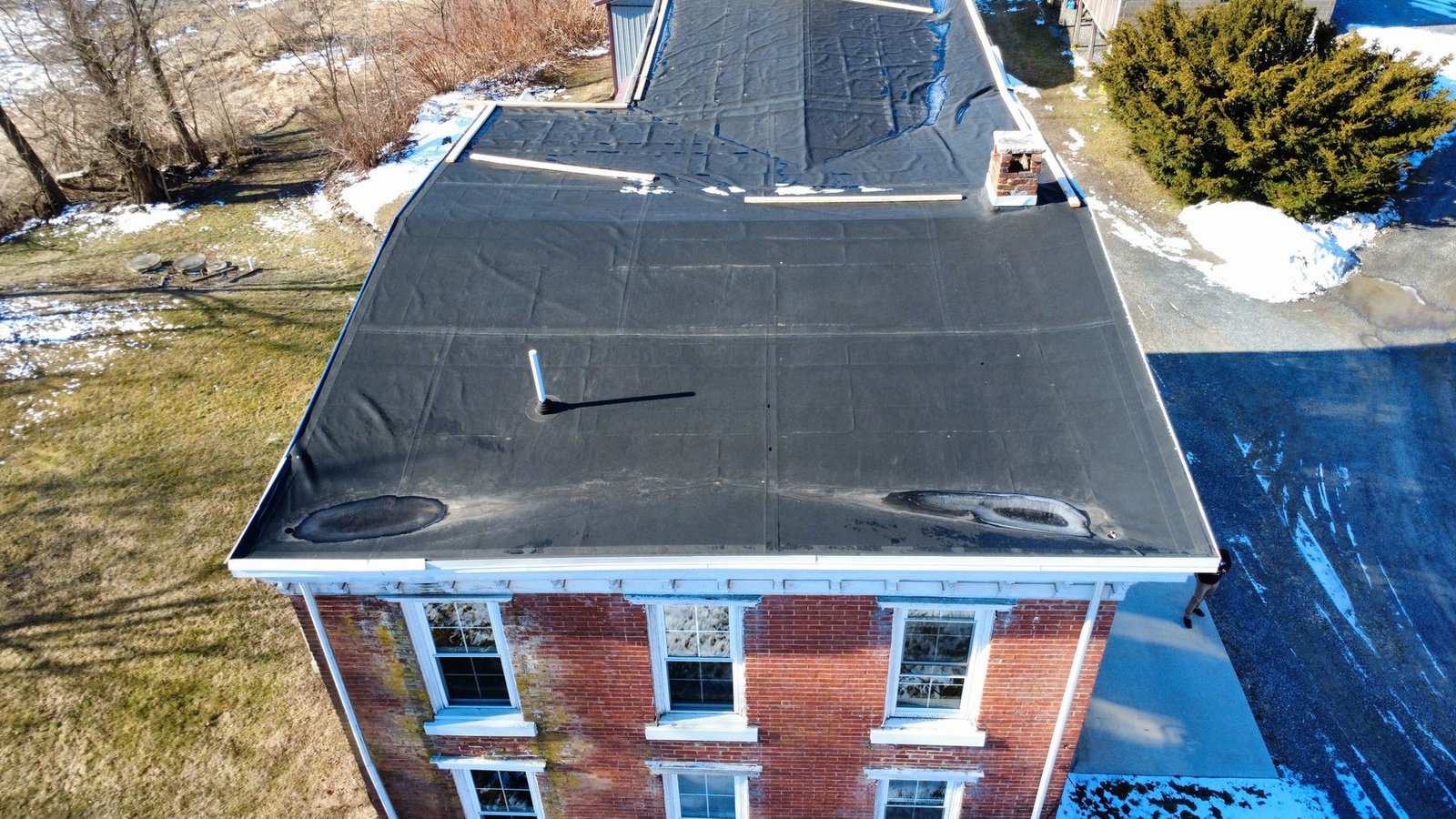 Before — aerial of historic 3-story brick building with failed flat roof, PA