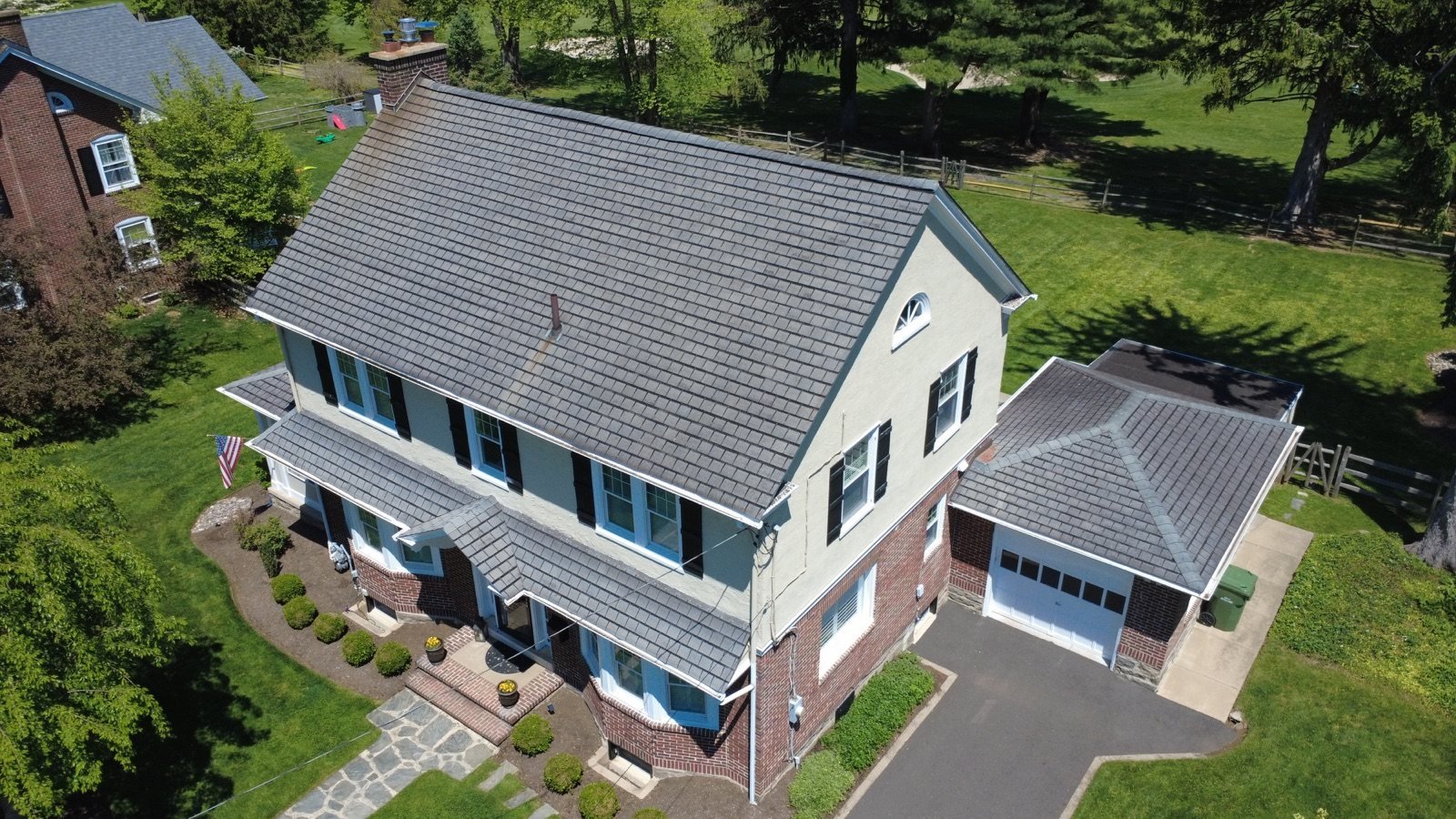Before — front corner aerial with worn shingles on main roof and garage, PA