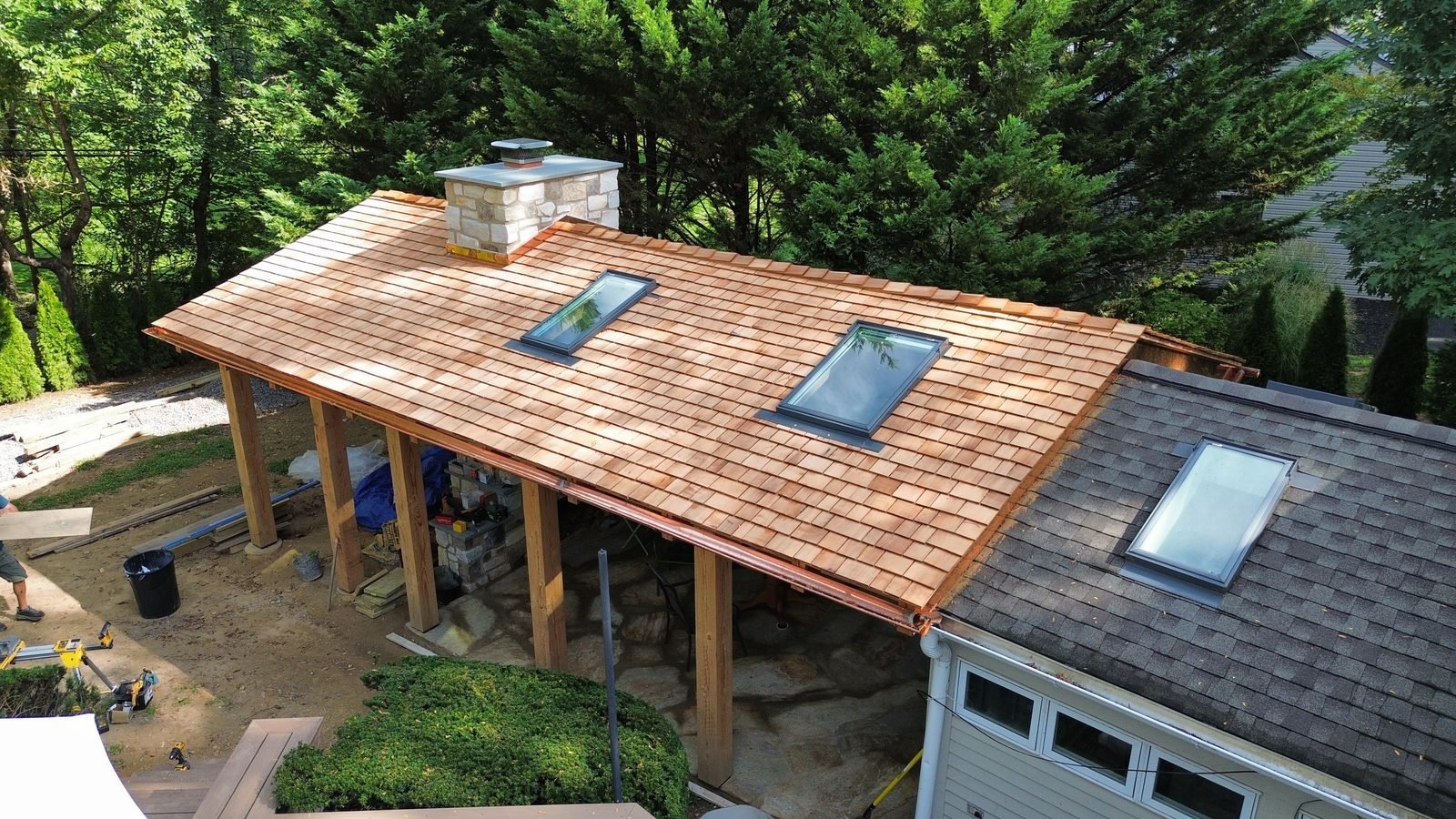 Phase 1 — new cedar shake porch roof with skylights and copper gutters beside the sunroom's original asphalt shingle roof, Bryn Athyn PA