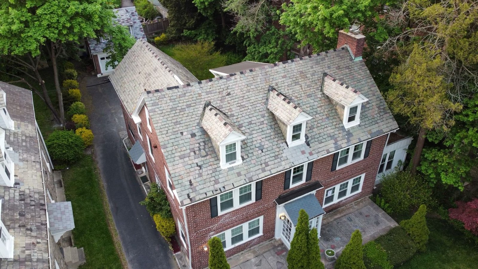 Before — front-left aerial showing worn dormers and shingles on brick colonial, PA