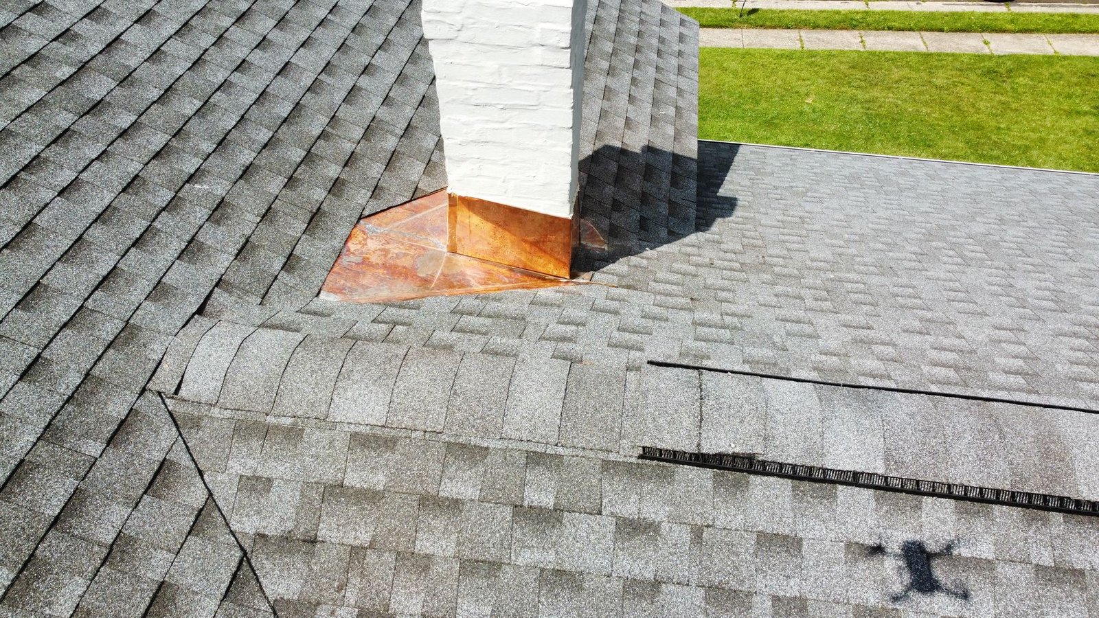 After — close-up of copper chimney saddle flashing on new charcoal shingles — Shelby Roofing Services PA