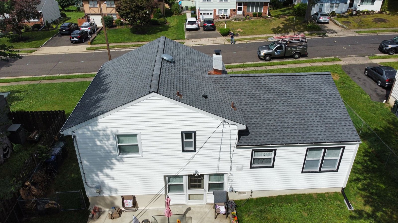 After — rear wide aerial showing completed roof with Shelby Roofing truck on street, PA