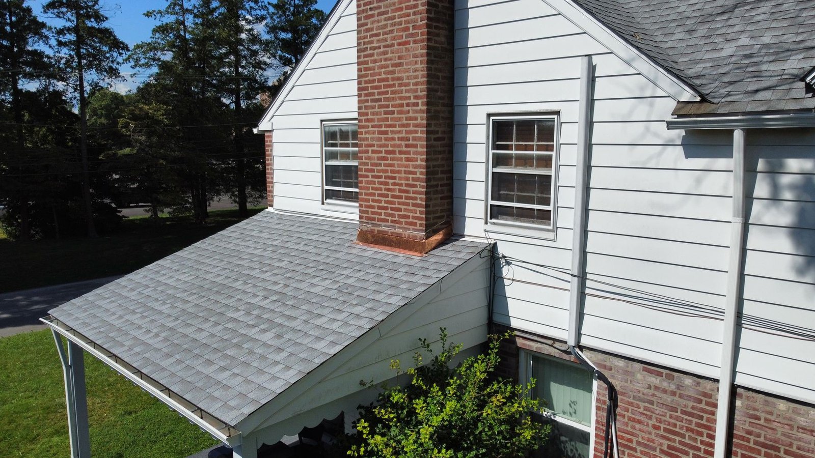 After — right side of brick colonial with new gray shingles and copper chimney flashing — Shelby Roofing Services PA
