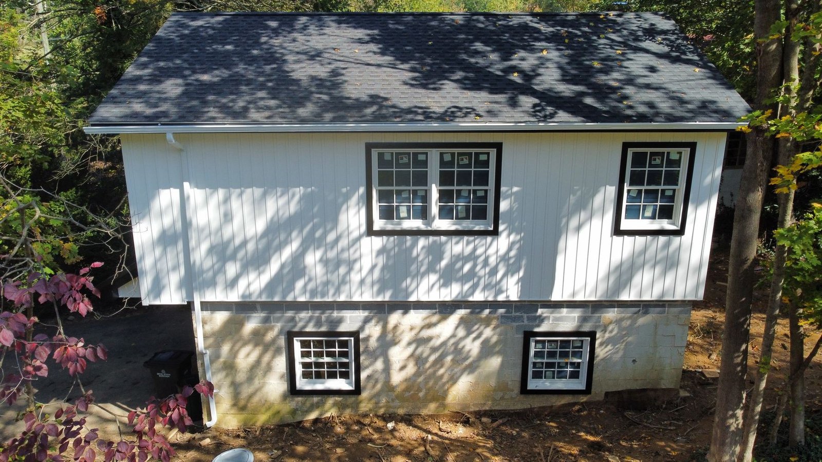 After — completed front showing new charcoal shingles, white board-and-batten siding, and black-trim windows — Shelby Roofing Services PA