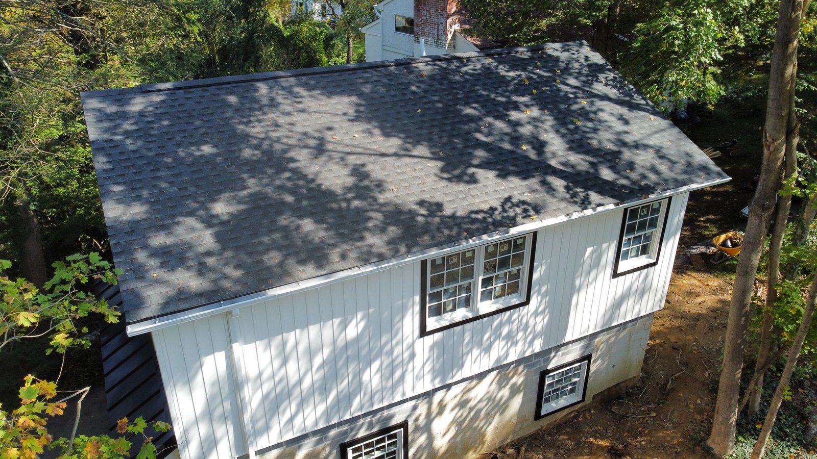 After — completed side view with new charcoal shingles and white board-and-batten siding — Shelby Roofing Services PA