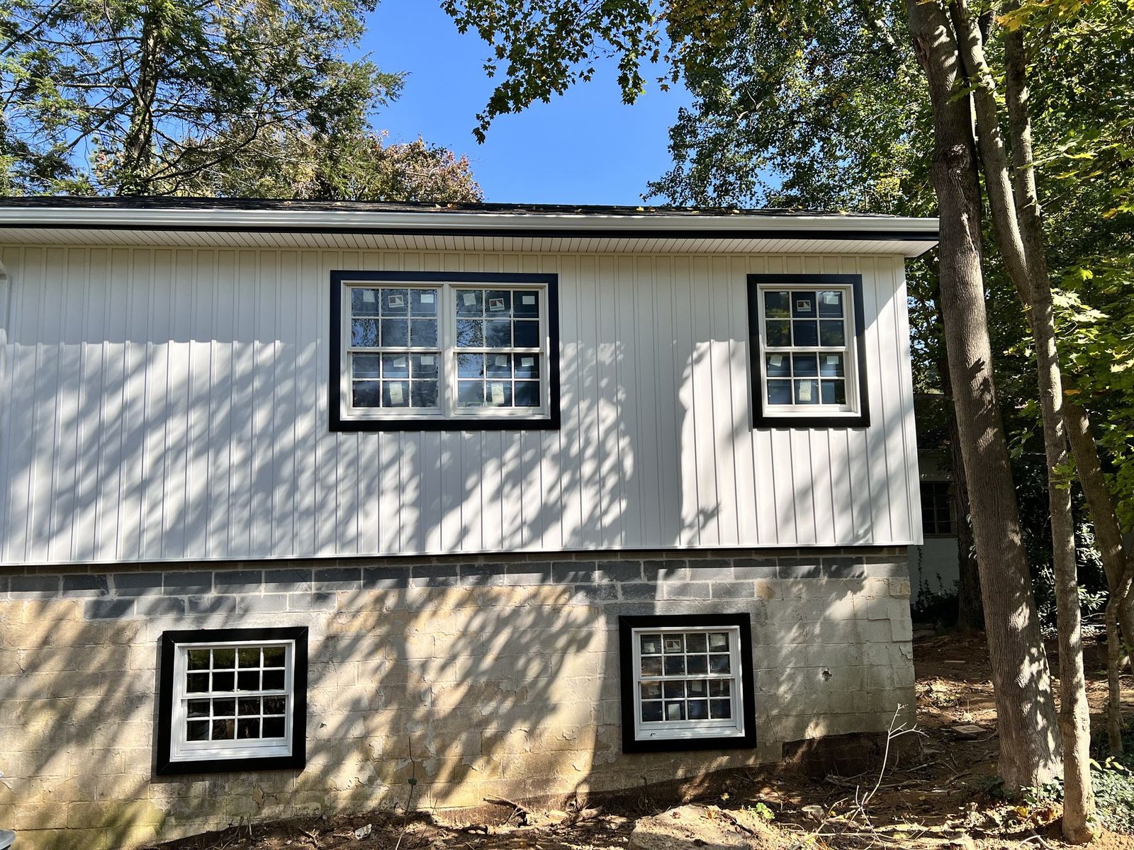 After — side view showing completed white board-and-batten siding with new windows and charcoal roof — Shelby Roofing Services PA