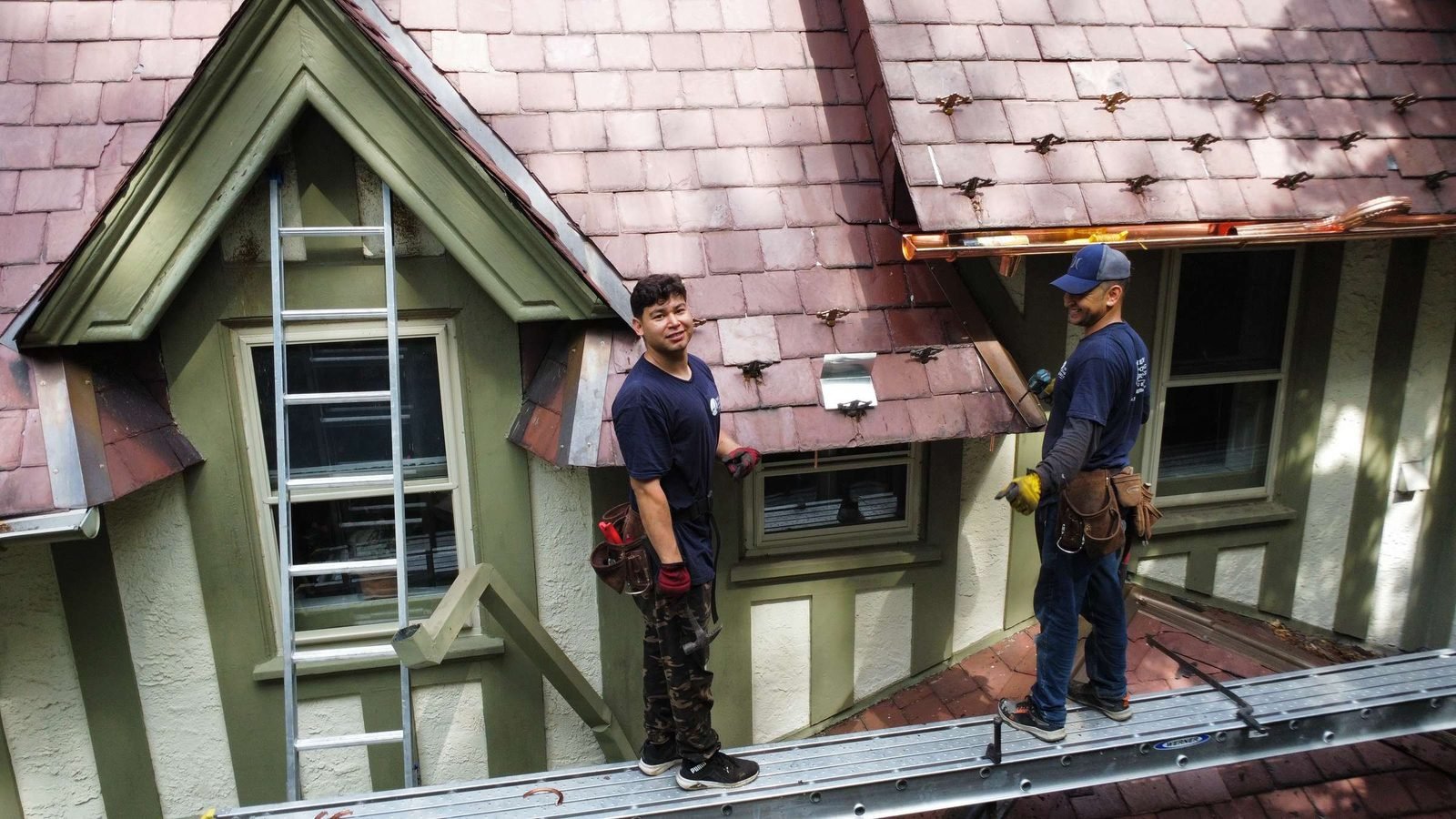 Shelby Roofing Services crew on a red slate roof with copper snow guards and copper gutters
