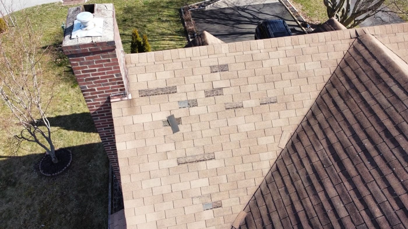 Drone view of shingles with multiple patched and deteriorated areas — signs of end-of-service-life roof