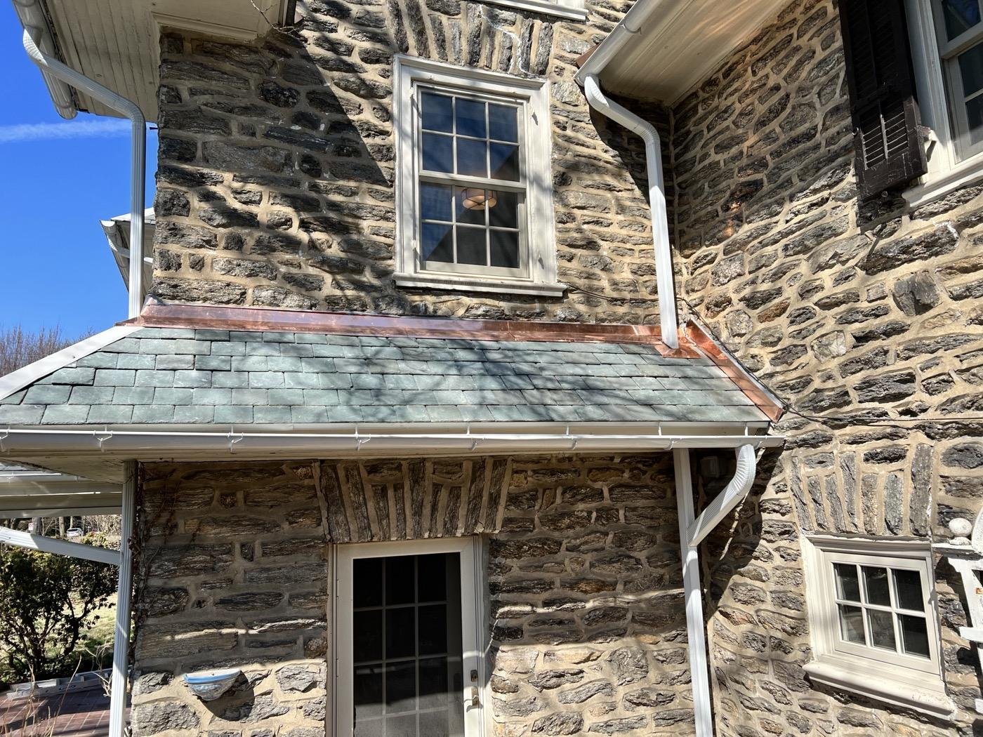 Completed natural slate roof with copper gutters on a stone colonial home — Shelby Roofing Services