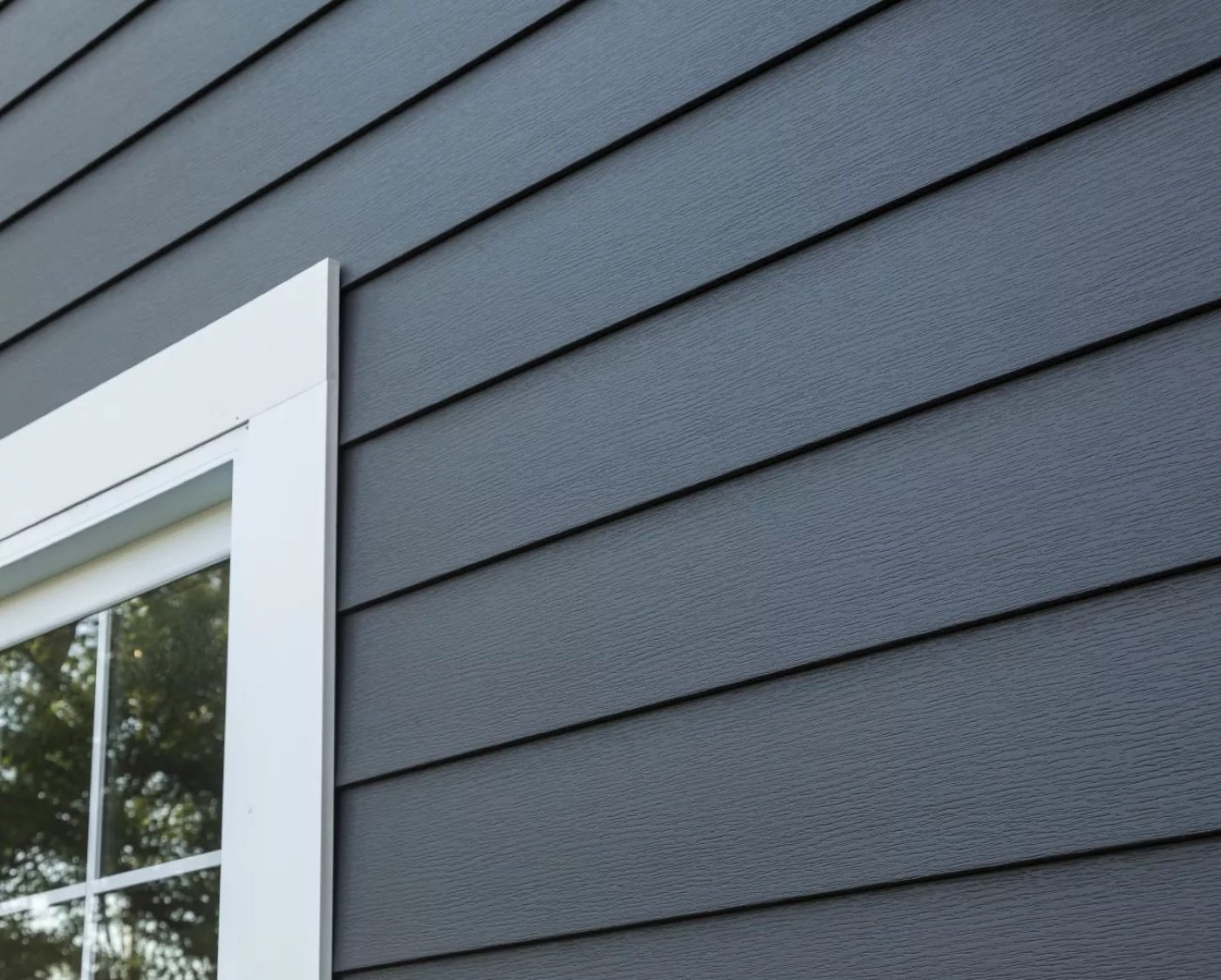 Close-up of precisely installed dark horizontal composite siding panels with clean white window trim — Shelby Roofing Services
